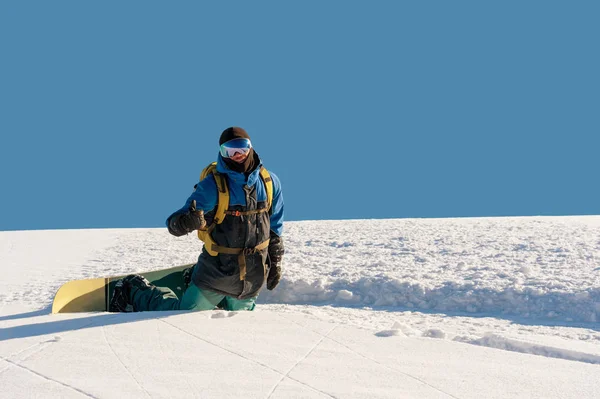 Sorrindo homem snowboarder descansando ajoelhado e mostrando polegares para cima — Fotografia de Stock
