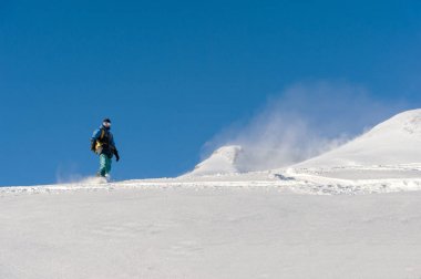Freeride snowboard kar toz mavi gökyüzüne karşı geride bırakarak bir karla kaplı yamaç rulo