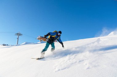 Freeride snowboard kar toz mavi gökyüzüne karşı geride bırakarak bir karla kaplı yamaç rulo