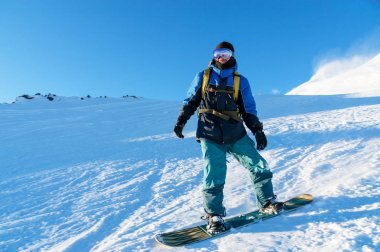 Freeride snowboard kar toz mavi gökyüzüne karşı geride bırakarak bir karla kaplı yamaç rulo