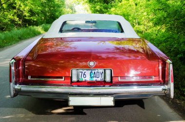 Nevinomyssc, Rusya Federasyonu - 13 Mayıs 2016: otomobiller. Eski Amerikan arabaları dışına fotoğraf. Cadillac Eldorado Cabrio 1976s. Bir ormandaki bir ülke yolda makinenin arka görünüm