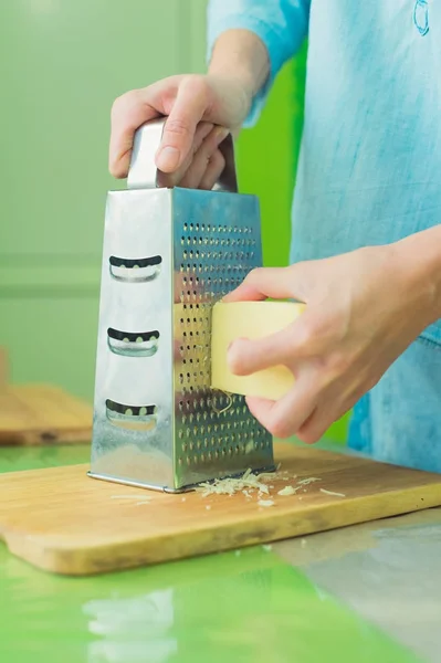 Close-up van een dames handen wrijven de Parmezaanse kaas op een metalen rasp. — Stockfoto