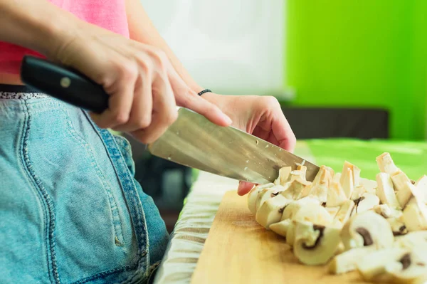 Female hands cut into large wooden mushrooms on a cutting board. — Stock Photo, Image