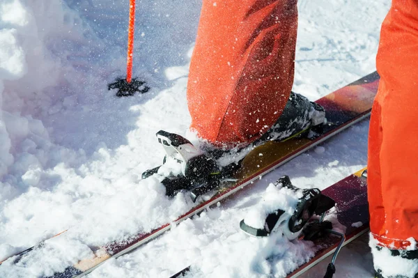 Pomarańczowy alpine buty narciarskie w narciarskich mount. Jeden rozruchu jest całkowicie ustalona na nartach, drugi nie. — Zdjęcie stockowe