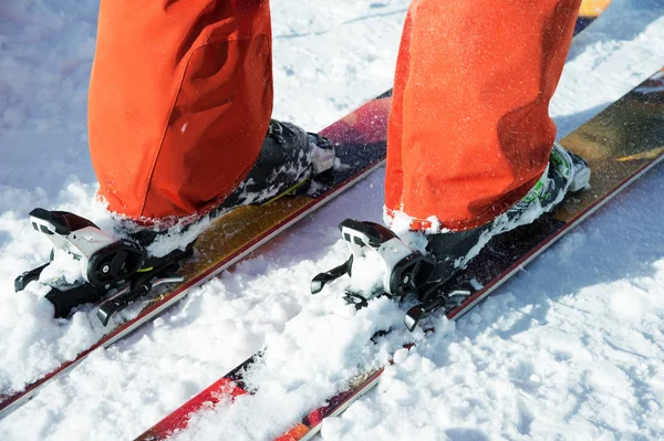 Pomarańczowy alpine buty narciarskie w narciarskich mount. Jeden rozruchu jest całkowicie ustalona na nartach, drugi nie. — Zdjęcie stockowe
