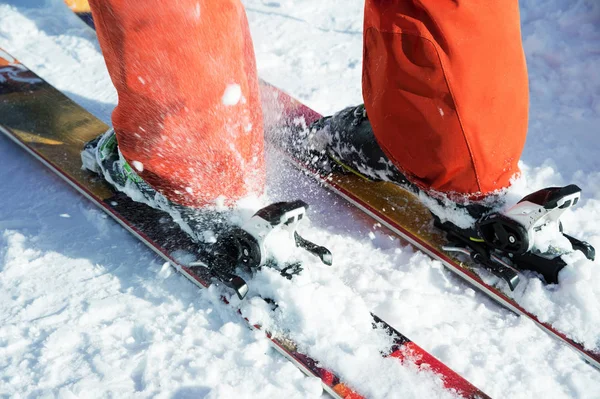 Pomarańczowy alpine buty narciarskie w narciarskich mount. Jeden rozruchu jest całkowicie ustalona na nartach, drugi nie. — Zdjęcie stockowe