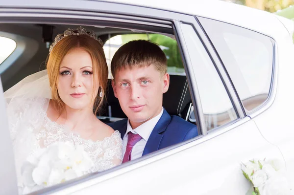 Porträt eines frisch vermählten Paares im Fenster eines Hochzeitswagens. Konzept eines glücklichen jungen Paares. — Stockfoto