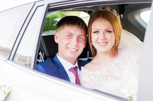 Porträt eines frisch vermählten Paares im Fenster eines Hochzeitswagens. Konzept eines glücklichen jungen Paares. — Stockfoto