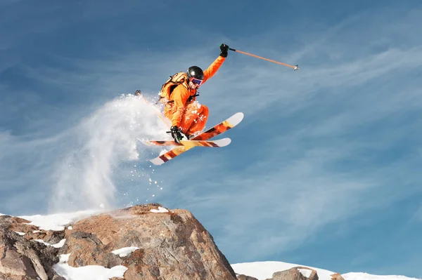 Narciarz sportowiec jest skakanie z wysokiej skały wysokie w górach. — Zdjęcie stockowe