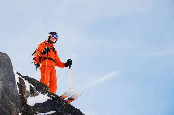 Επαγγελματίας σκιέρ-αθλητής που στέκεται στην άκρη του ένα ψηλό βράχο ενάντια σε ένα καταγάλανο ουρανό σε μια ηλιόλουστη ημέρα — Φωτογραφία Αρχείου