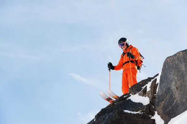 Profi-Skirennfahrer steht an einem sonnigen Tag am Rande einer hohen Klippe vor blauem Himmel — Stockfoto