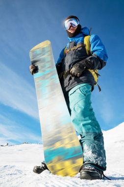 Onun snowboard mavi gökyüzü ile profesyonel bir snowboard duruyor