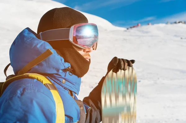 Um snowboarder profissional está com seu snowboard. Close-up. Retrato de um freerider — Fotografia de Stock