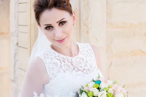 Portrait of a beautiful bride in a white dress and a bouquet of flowers in her hands — Stock Photo, Image