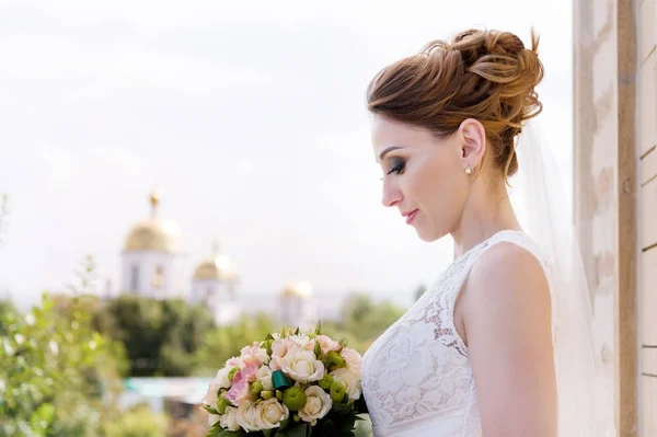 Красиві нареченої в день весілля з букетом в руку на тлі православних християнської Церкви. — стокове фото