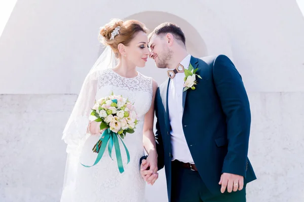 Ritratto di una bella coppia in luna di miele in un giorno di nozze con un bouquet in mano sullo sfondo di un monumento cristiano ortodosso con angeli . — Foto Stock