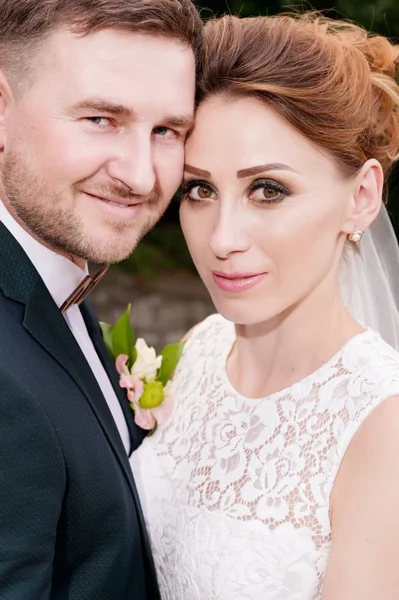 Nahaufnahme Porträt eines liebenden Brautpaares vor dem Hintergrund sommerlichen Grüns neben. — Stockfoto