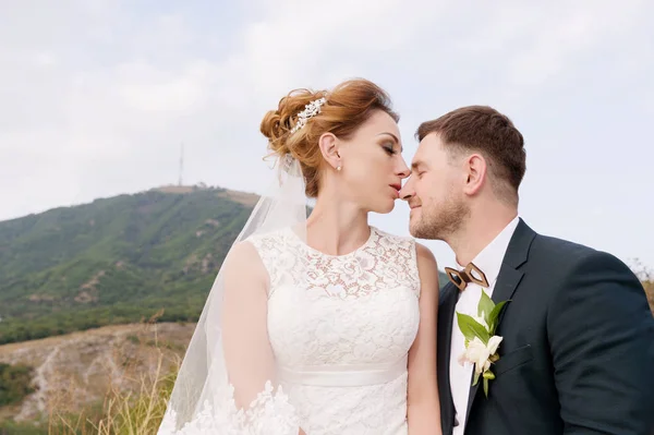 Um casal amoroso de recém-casados se senta no fundo da paisagem urbana de uma pequena cidade resort no Cáucaso. recém-casados gentilmente acariciar uns aos outros — Fotografia de Stock