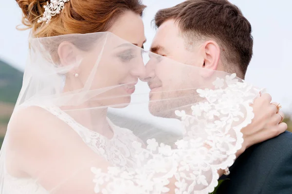 Um casal amoroso de recém-casados se senta no fundo da paisagem urbana de uma pequena cidade resort no Cáucaso. recém-casados gentilmente acariciar uns aos outros — Fotografia de Stock