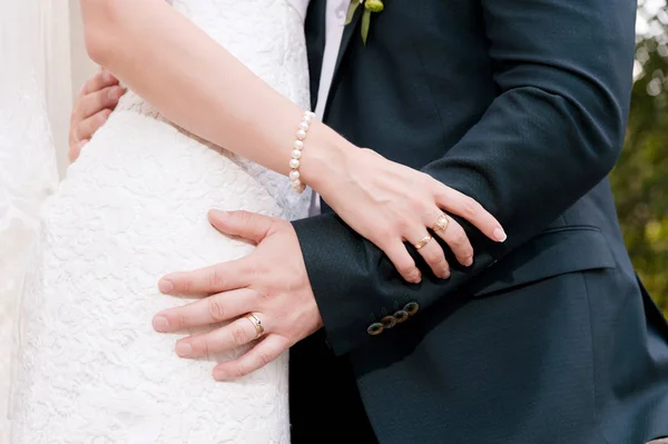 Gros plan des mains dans les câlins des jeunes mariés le jour du mariage . — Photo