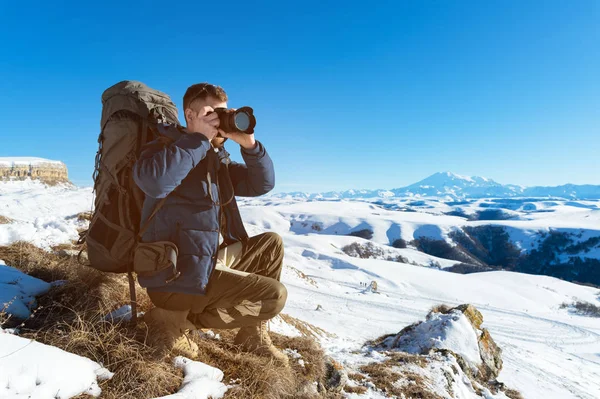 Portrét vousatého bokovky, fotograf s batohem a v sluneční brýle fotí své DSLR — Stock fotografie
