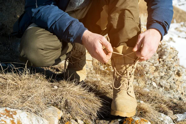 Крупный план путешественника в горах зимой, завязывающего шнурки на ботинках — стоковое фото