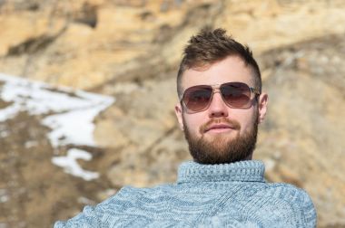 Güneş gözlüğü ve doğa üzerinde kış dinlenme örme gri kazak bir gezgin hipster portresi