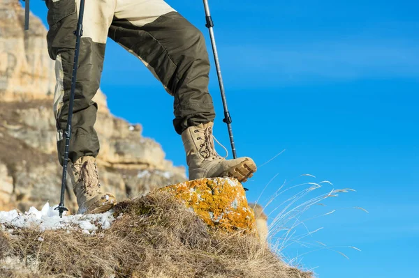 Detail nohy turisty v turistických botách s holemi pro Nordic walking stojící na kameni kámen v horách — Stock fotografie