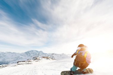 Bir snowboard kar maskesi ve bir sırt çantası içinde bir kar toz mavi gökyüzü ve batan güneşin karşı geride bırakarak karla kaplı yamacında biniyor