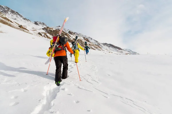 A group of three freeriders climb the mountain for backcountry skiing along the wild slopes of the — Stock Photo, Image