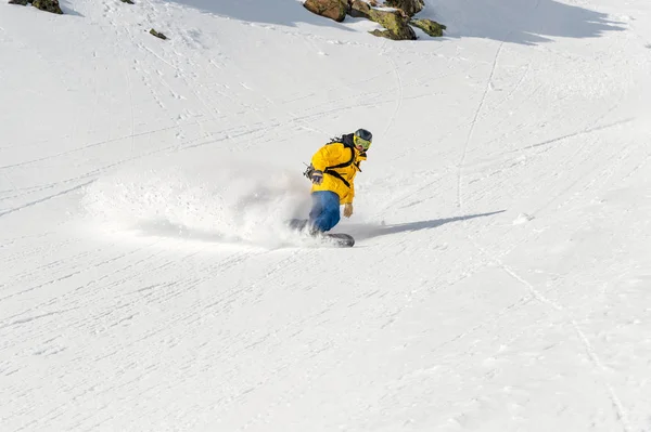 Чоловік сноубордист фрірайдер спускається за межі країни на великій швидкості зі схилу — стокове фото
