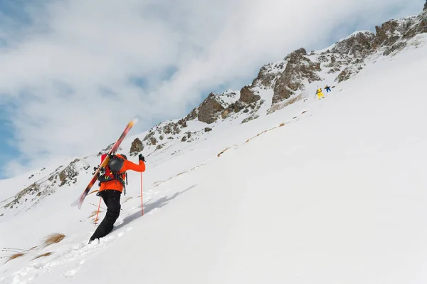 O freerider do esqui sobe a inclinação no pó profundo da neve com o equipamento na parte traseira fixado na mochila . — Fotografia de Stock
