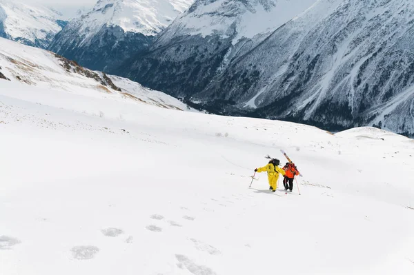 Deux freerider montent la pente dans de la neige poudreuse profonde avec l'équipement sur le dos fixé sur le sac à dos . — Photo