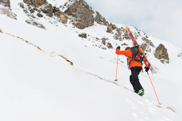 De ski-freerider klimt de helling tot diepe sneeuw poeder met de apparatuur op de achterkant gefixeerd op de rugzak. — Stockfoto