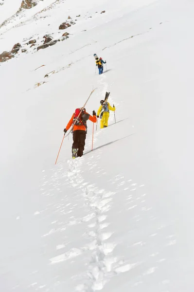 Two ski freerider climbs the slope into deep snow powder with the equipment on the back fixed on the backpack. — Stock Photo, Image