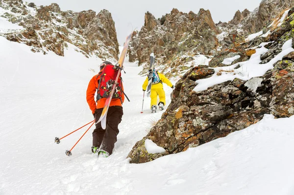 Schiorii extremi urcă în vârf de-a lungul couloir-ului dintre stânci înainte de coborârea freeride backcountry — Fotografie, imagine de stoc