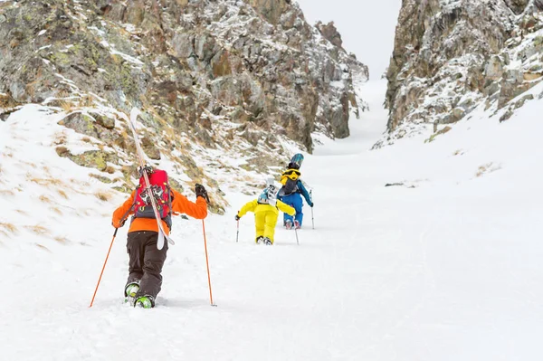 Les skieurs extrêmes montent au sommet le long du couloir entre les rochers avant la descente de l'arrière-pays freeride — Photo