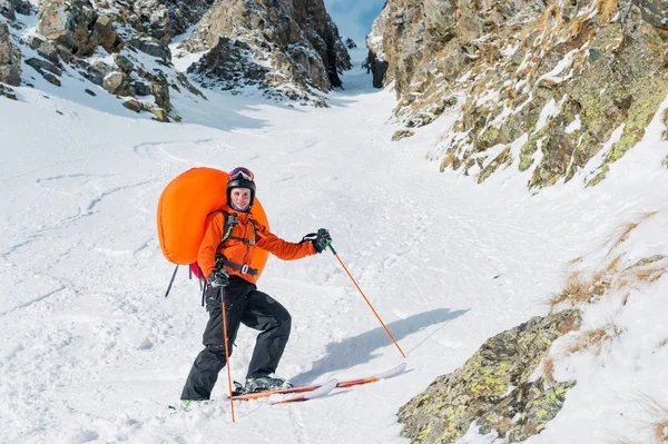 Portret van een lachende gelukkig freeride backcountry skiër met een geopende lawine vattenproducenten abs in een rugzak. — Stockfoto