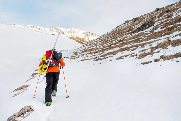 De ski-freerider klimt de helling tot diepe sneeuw poeder met de apparatuur op de achterkant gefixeerd op de rugzak. — Stockfoto