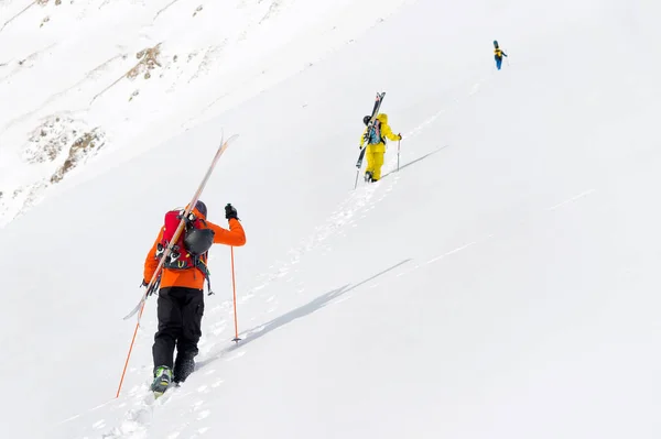 Două freerider de schi urcă pârtia în praf de zăpadă adânc cu echipamentul de pe spate fixat pe rucsac . — Fotografie, imagine de stoc