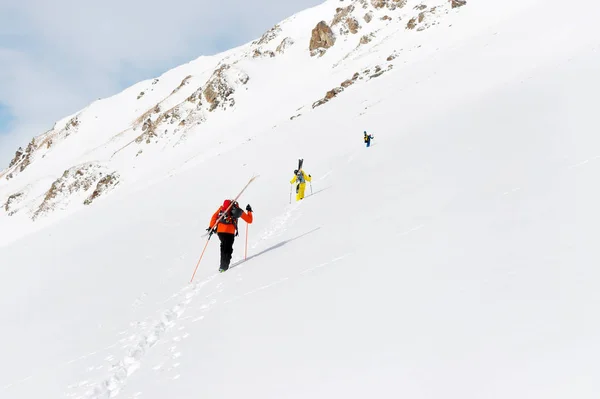 Două freerider de schi urcă pârtia în praf de zăpadă adânc cu echipamentul de pe spate fixat pe rucsac . — Fotografie, imagine de stoc