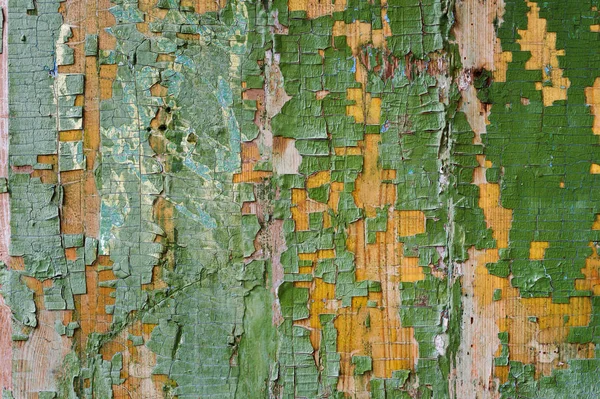 A large textured background the old yellow board is covered with green paint. Exfoliating green paint in large pieces missing on the wooden coating. The concept of ruin and vintage antiquity — Stock Photo, Image