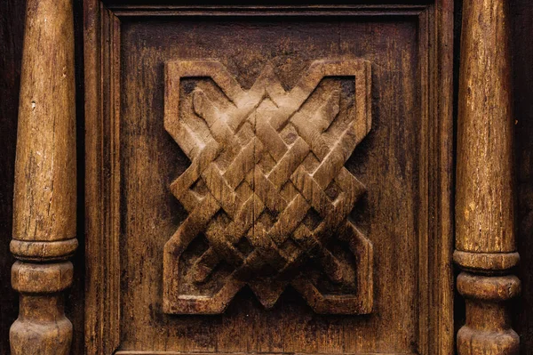 Vintage background. Elements of an old carved wooden door decorated with voluminous carved wooden elements imitating the weaving. A vintage concept of old antiques. Varnished old mahogany — Stock Photo, Image