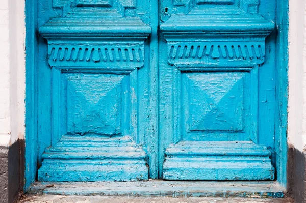 Close-up the Element of blue many times painted cracked double-barreled wooden vintage door of the last century with a post slit.