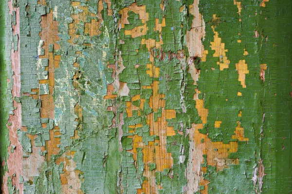 Um grande fundo texturizado a antiga placa amarela é coberta com tinta verde. Esfoliante tinta verde em pedaços grandes faltando no revestimento de madeira. O conceito de ruína e antiguidade vintage — Fotografia de Stock