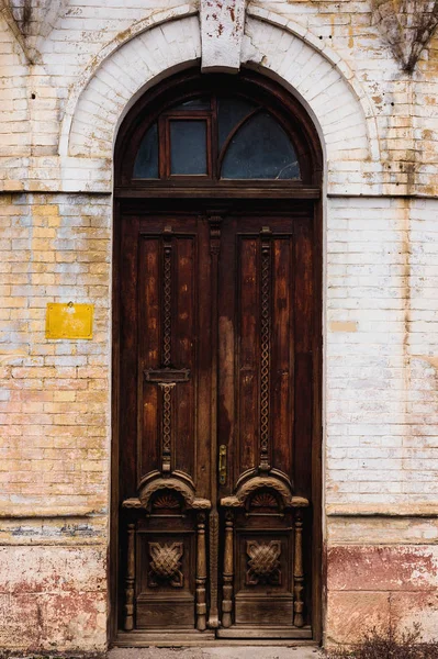 Fasada budynku dawnej z starych liściach dwukrotnie brązowy drewniany drzwi ozdobione obszerne rzeźbione wzory drewna w archway bielonymi cegły. Koncepcja Europejskiej antyczny — Zdjęcie stockowe