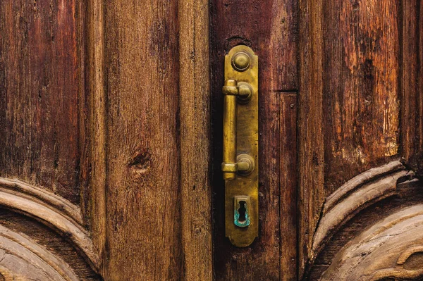 Вінтажний фон. Латунна стара ручка з елементами різьблених дерев'яних дверей, прикрашених масивним дерев'яним імітаційним плетінням. Стара концепція старих антикваріатів. Пофарбовані старі махагони — стокове фото