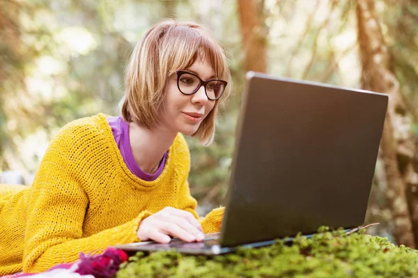 Bir serbest meslek sahibi kız portre sarı kazak ve düşünceli bir iğne yapraklı orman doğada içinde belgili tanımlık laptop perde bakarak gözlük yakın çekim Toned görüntüsü. Freelancing özgürlük kavramı — Stok fotoğraf