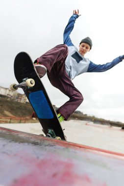 Genç kaykaycı şapkalı bir rampa skate Park bulutlu bir gökyüzü ve alan uyku karşı kayalar hile yok. Kentsel spor tarzda kavramı
