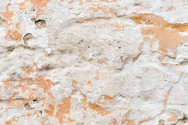 Texturierter Grunge-Hintergrund. volumetrische verputzte Wand mit einer mehrschichtigen rissigen Beschichtung. Orangenchips an der weiß getünchten Wand. Grunge-Textur mit tiefem Muster — Stockfoto